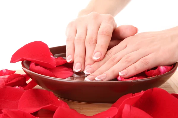 Mains avec manucure française relaxante dans un bol d'eau aux pétales de rose — Photo