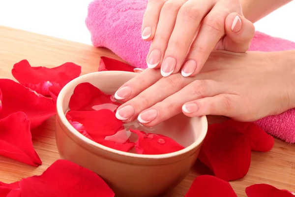 Hands with french manicure relaxing in bowl of water with rose — Stock Photo, Image