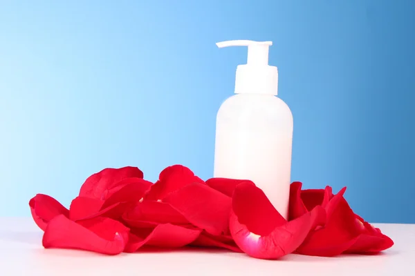 Wanne mit einer Creme mit roten Rosenblättern auf blauem Hintergrund — Stockfoto