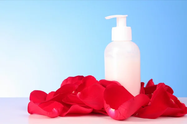 Tub with a cream with a red rose petals on blue background — Stock Photo, Image