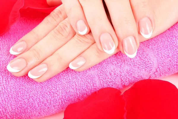 Beaitiful womans hands with manicure on the towel and rose peta — Stock Photo, Image