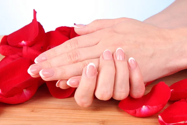 Beaitiful mujeres manos con manicura en los pétalos de rosa —  Fotos de Stock