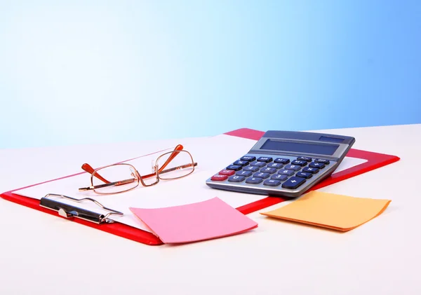 Óculos, calculadora e papel sobre mesa — Fotografia de Stock