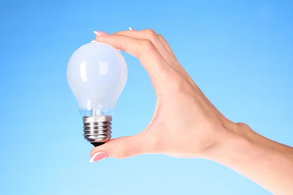Hand with lightbulb on blue background — Stock Photo, Image