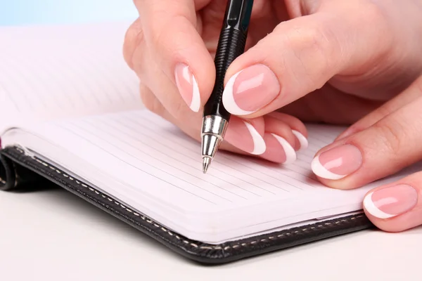Γυναίκα χέρι εγγράφως στο σημειωματάριο στο τραπέζι — Φωτογραφία Αρχείου