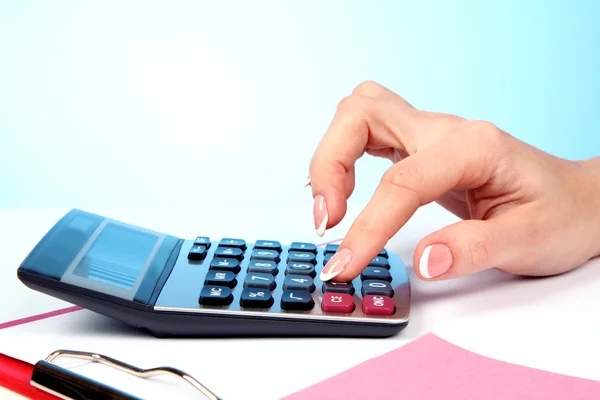 Dedos e calculadora no fundo azul — Fotografia de Stock