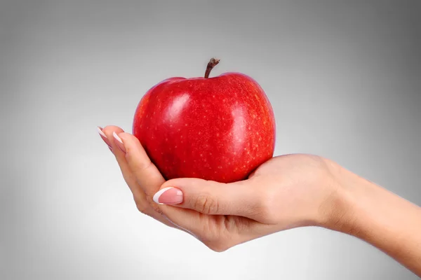Een appel op de hand op grijze achtergrond — Stockfoto