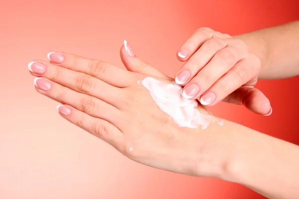Closeup of beautiful female hands applying hand cream on red ba — Stock Photo, Image
