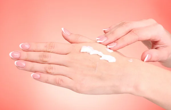 Primer plano de hermosas manos femeninas aplicando crema de manos sobre ba roja —  Fotos de Stock