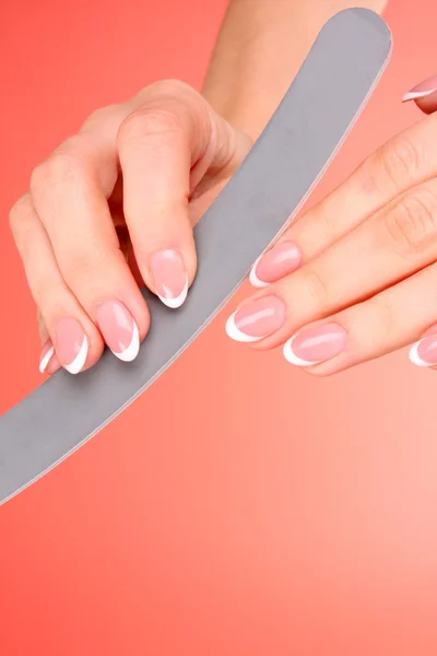 Woman hands using emery board on the red background — Stock Photo, Image