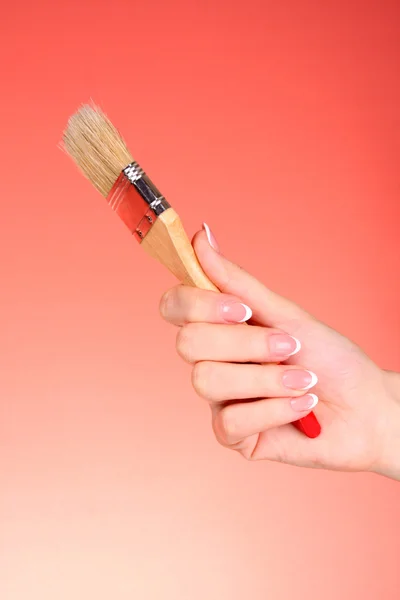 Mão com escova no fundo vermelho — Fotografia de Stock