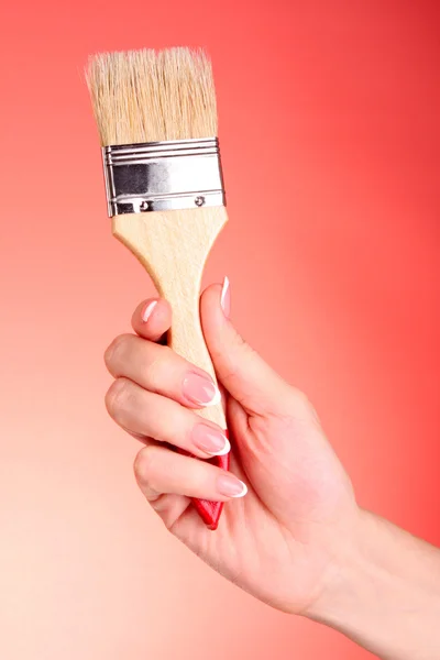 Hand mit Pinsel auf rotem Hintergrund — Stockfoto