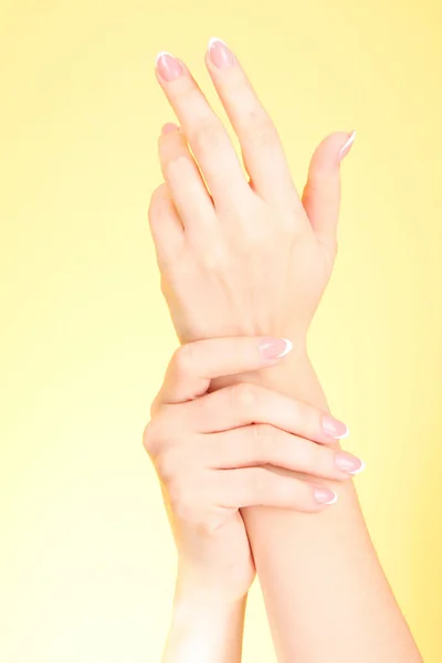 Mulher tocando as mãos no fundo amarelo — Fotografia de Stock