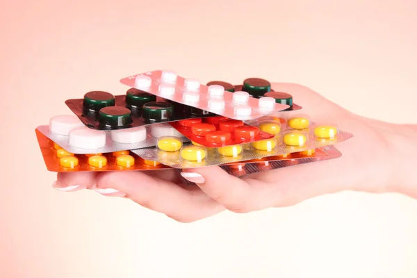 stock image Woman hand with a lot of pills on red background