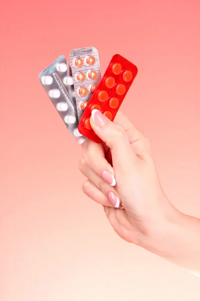 Kvinnor händer med tabletter mot röd bakgrund — Stockfoto
