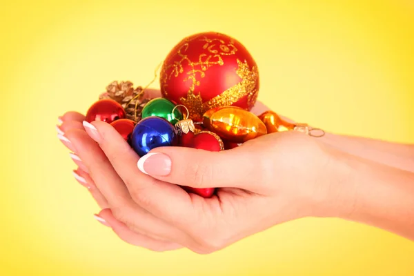 Mãos e decoração de Natal no fundo amarelo — Fotografia de Stock