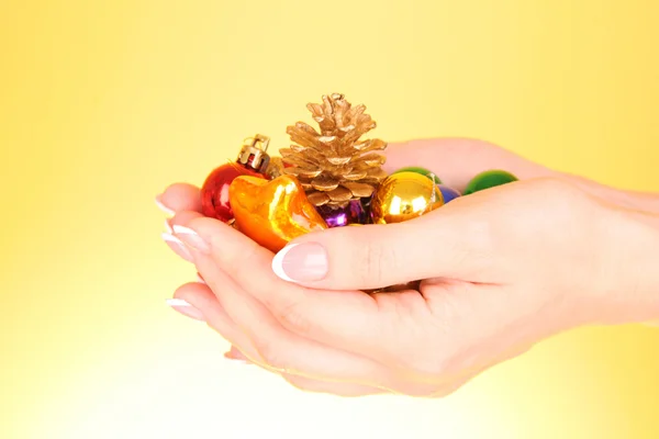 Hände und Weihnachtsdekoration auf gelbem Hintergrund — Stockfoto