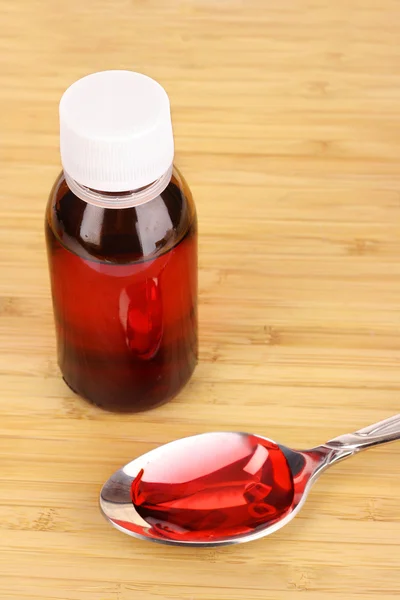 Spoon of cough medicine and bottle on the table — Stock Photo, Image