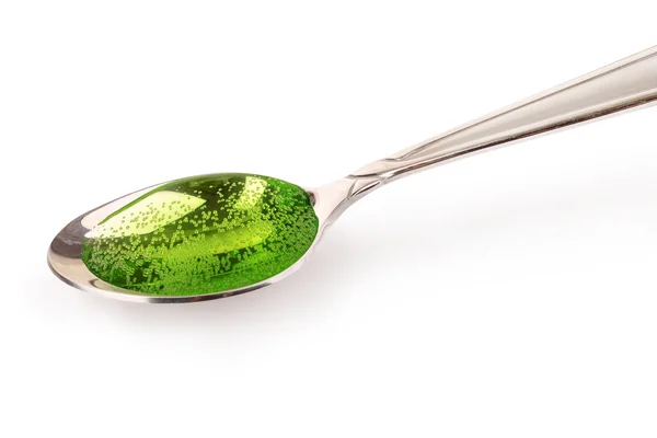 Xarope de tosse verde em colher de prata — Fotografia de Stock