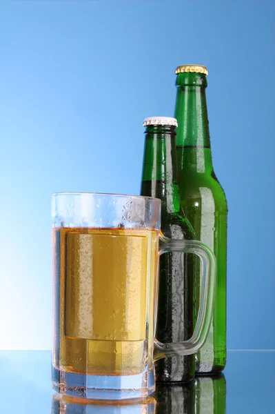Bottles with beer and cup on blue background — Stock Photo, Image