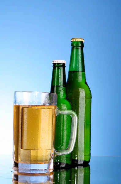 Bottles with beer and cup on blue background — Stock Photo, Image