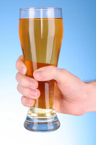 Cup of beer in hand on blue background — Stock Photo, Image
