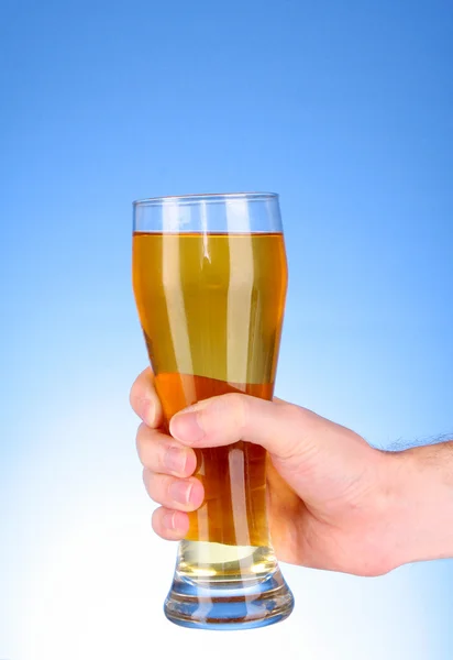 Cup of beer in hand on blue background — Stock Photo, Image