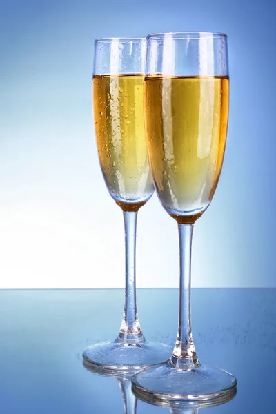 Glass with champagne on blue background — Stock Photo, Image