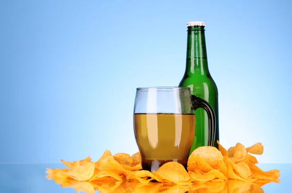 Bottles with beer, cup and potato chips on blue background — Stock Photo, Image
