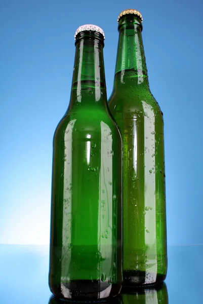 Бутылка пива на синем фоне — стоковое фото