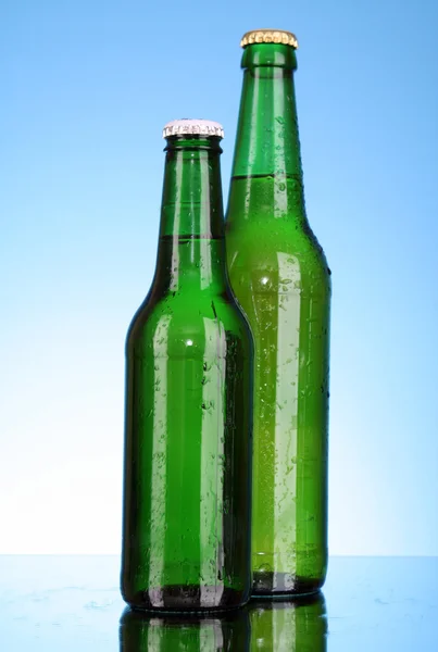 Бутылка пива на синем фоне — стоковое фото