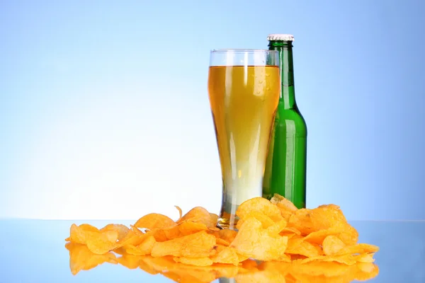 Bottle with beer, cup and potato chips on blue background — Stock Photo, Image