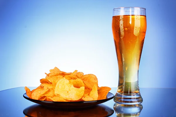 Beer and potato chips on blue background — Stock Photo, Image
