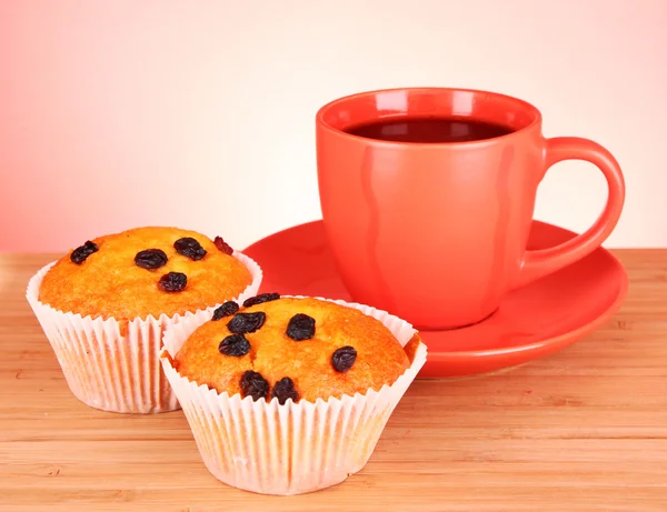 Muffins with raisins and red cup on wooden surface — Stock Photo, Image