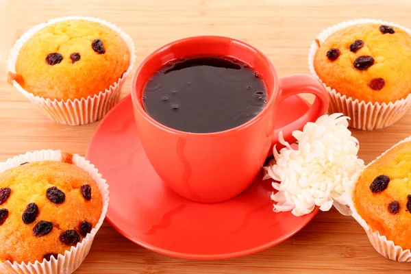 stock image Muffins with raisins and red cup on wooden surface