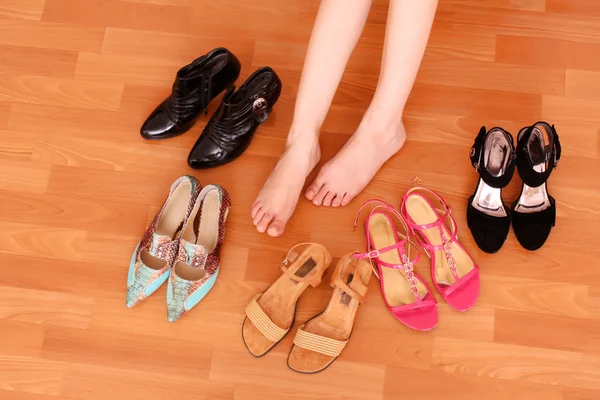 Zbliżenie kobiety nogi na podłogę i wiele obuwie wokół — Zdjęcie stockowe