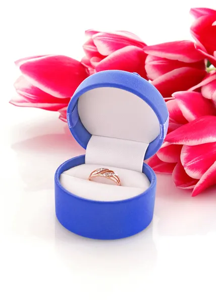 Zlatý zásnubní prsten v poli na pozadí květiny — Stock fotografie