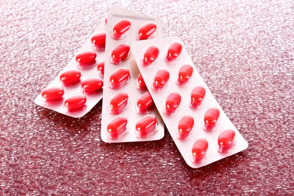 Red capsules of vitamins on a brown background — Stock Photo, Image