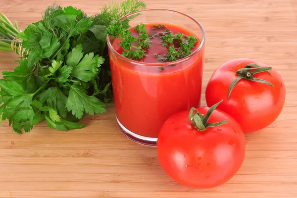 Vaso de jugo de tomate fresco y tomates alrededor del vaso en th — Foto de Stock