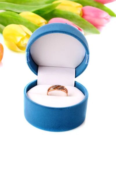 Золотое обручальное кольцо в коробке на фоне цветов — стоковое фото