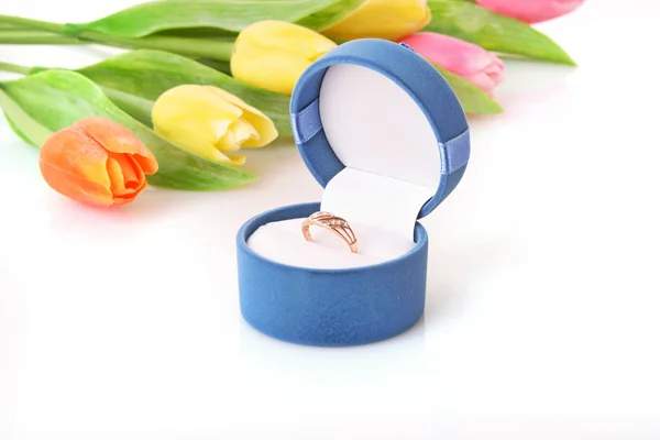 Gold engagement ring in box on the flowers background — Stock Photo, Image