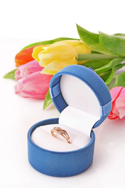 Gold engagement ring in box on the flowers background — Stock Photo, Image