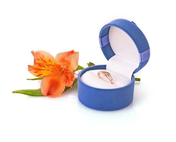 Золотое обручальное кольцо в коробке на фоне цветов — стоковое фото