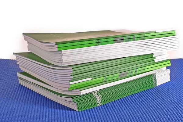 흰색 배경에 고립 된 녹색 잡지의 더미 — 스톡 사진