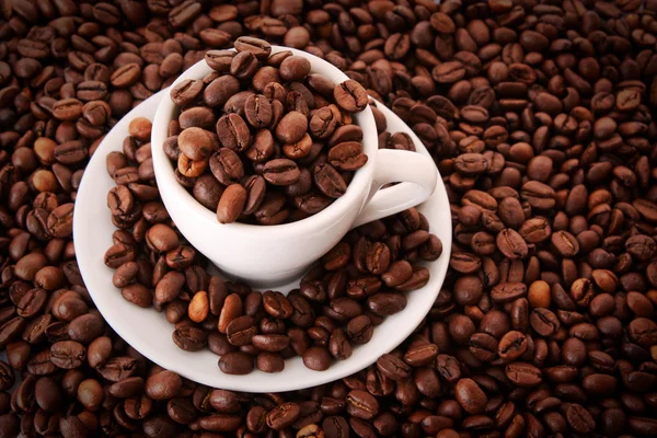 Kleine weiße Tasse Kaffee mit Kaffeekorn auf Kornhintergrund — Stockfoto