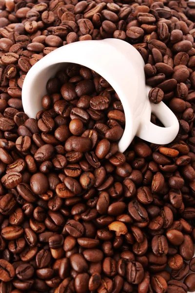 Pequeña taza de café blanco con grano de café sobre fondo de grano — Foto de Stock
