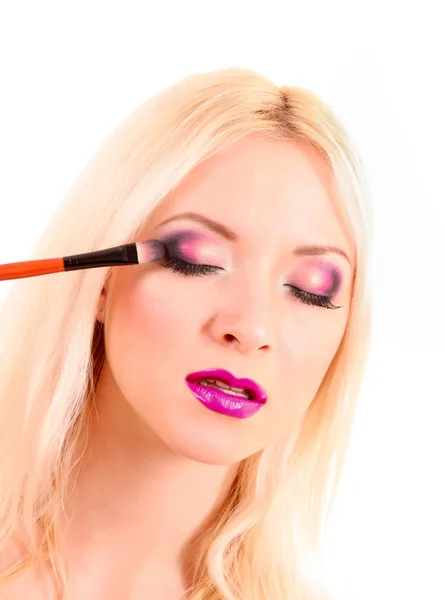 Schöne junge blonde Frau mit hellem Make-up und Pinsel auf wh — Stockfoto