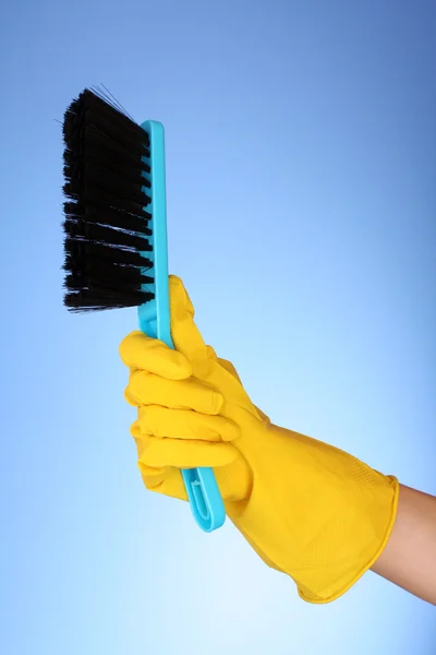 Mão com espanador e escova em azul — Fotografia de Stock