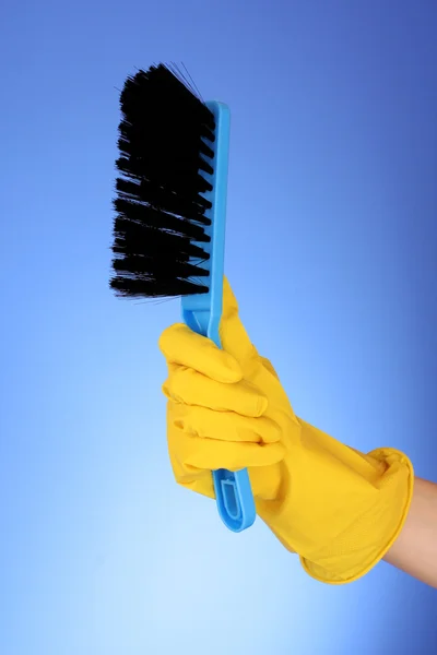 Hand with dustpan and brush on blue — Stock Photo, Image