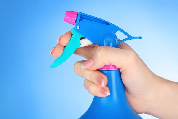 Mãos com spray sobre fundo azul — Fotografia de Stock